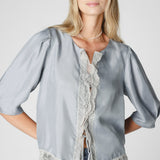 Blusa Witty de la marca P-2025-623, vista frontal, con diseño moderno y detalles elegantes en tejido ligero y color neutro.