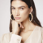 Aros Melina de la marca BI-2024-240, accesorios elegantes con detalles dorados y diseño moderno, en un fondo neutro.