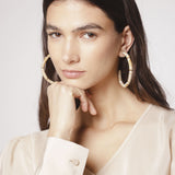 Aros Melina de la marca BI-2024-240, accesorios elegantes con detalles dorados y diseño moderno, en un fondo neutro.
