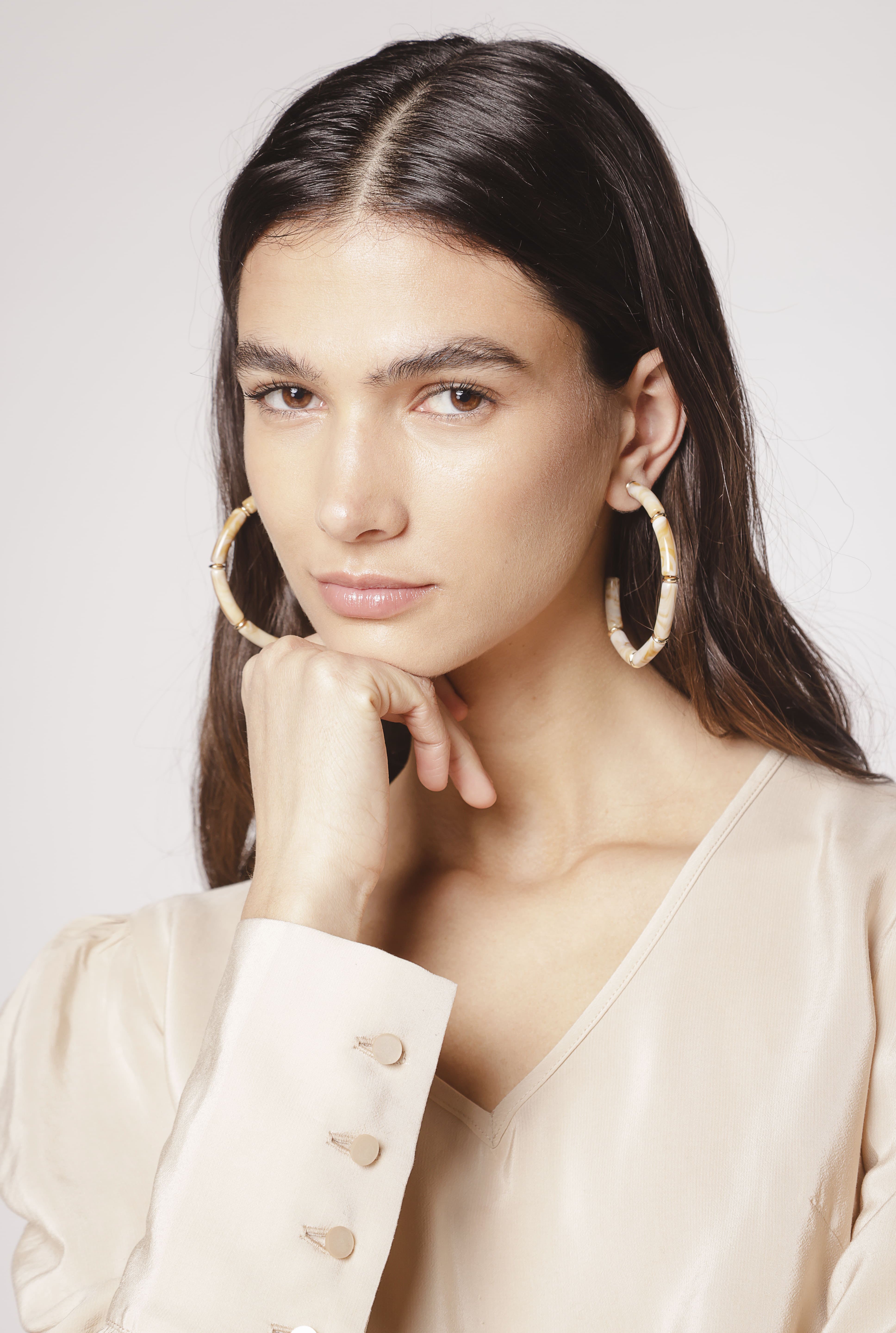 Aros Melina de la marca BI-2024-240, accesorios elegantes con detalles dorados y diseño moderno, en un fondo neutro.