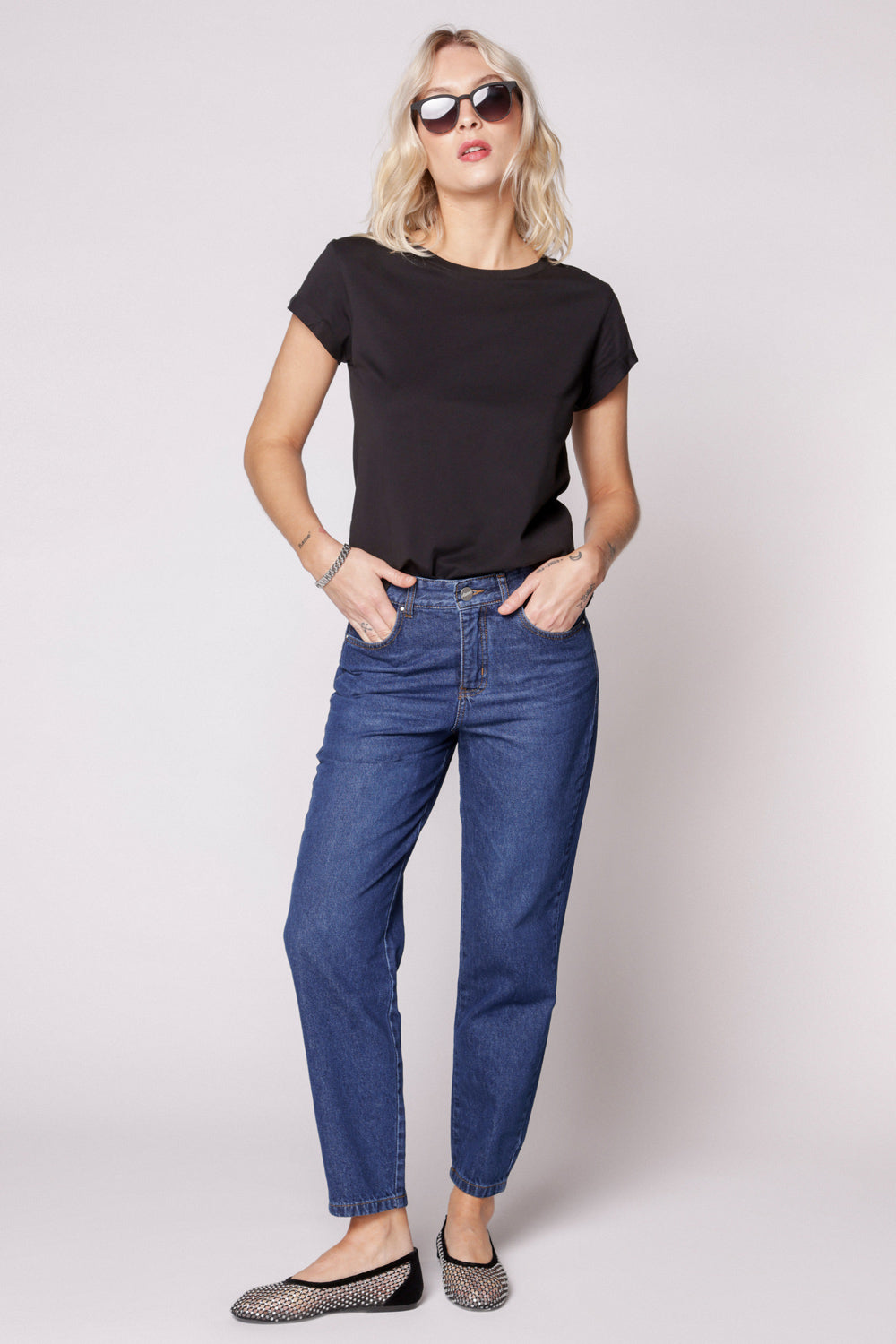 Modelo con jeans mom fit azul oscuro y polera negra sin mangas, vista frontal