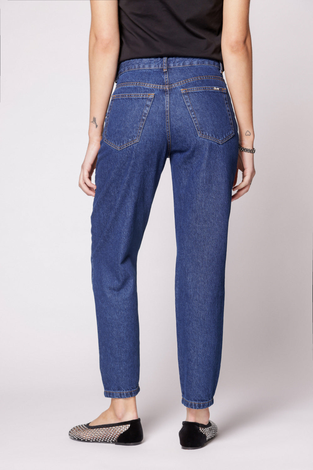 Modelo con jeans mom fit azul oscuro y polera negra sin mangas, vista frontal