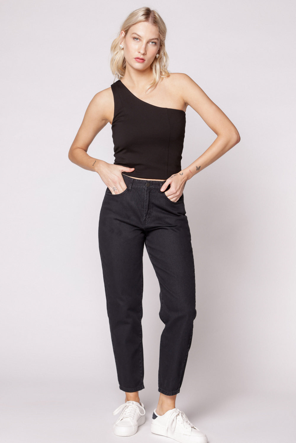 Modelo con jeans mom fit negros y top negro sin mangas, en pose frontal casual
