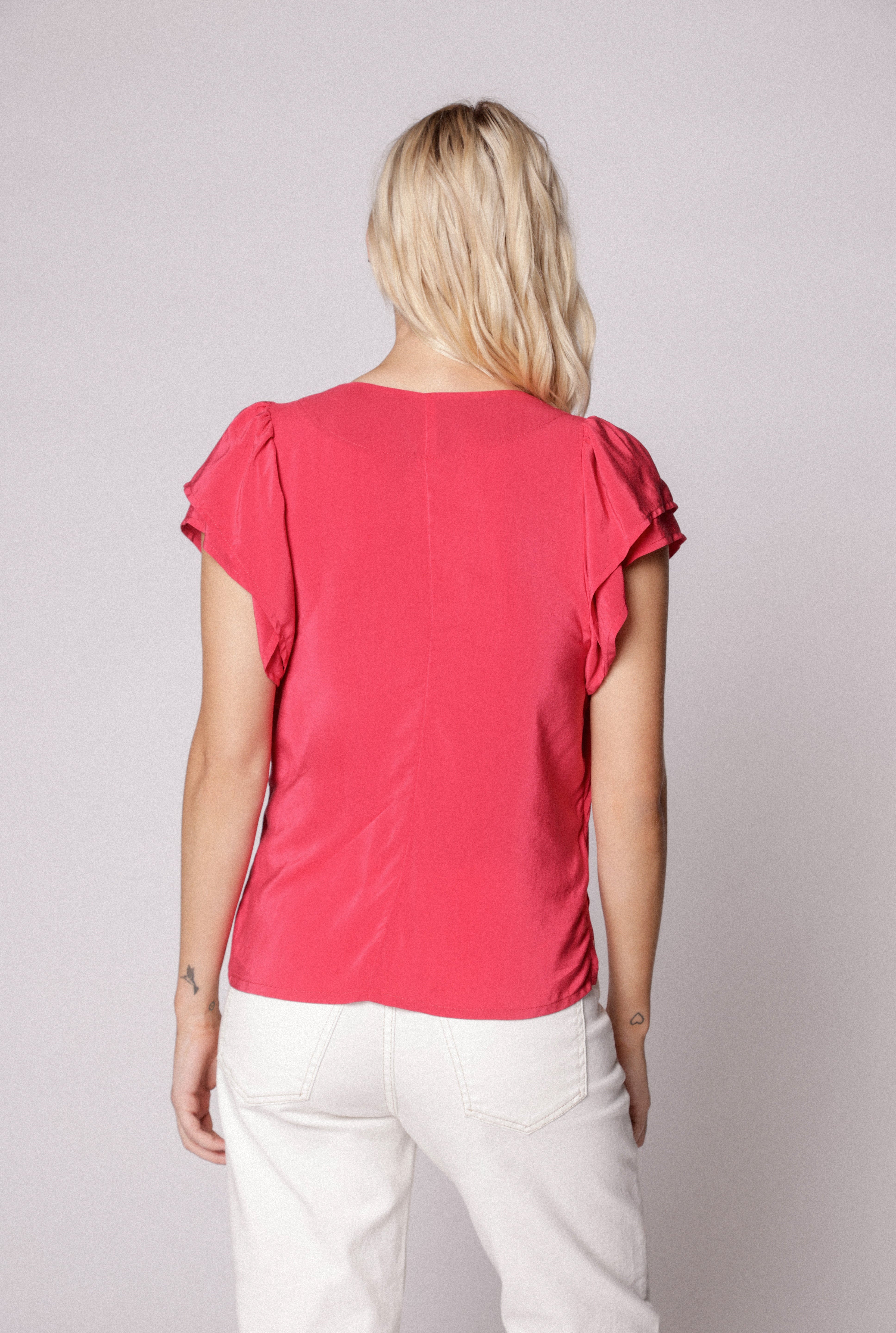 Vista trasera de jeans mom fit blanco con top fucsia en pose relajada
