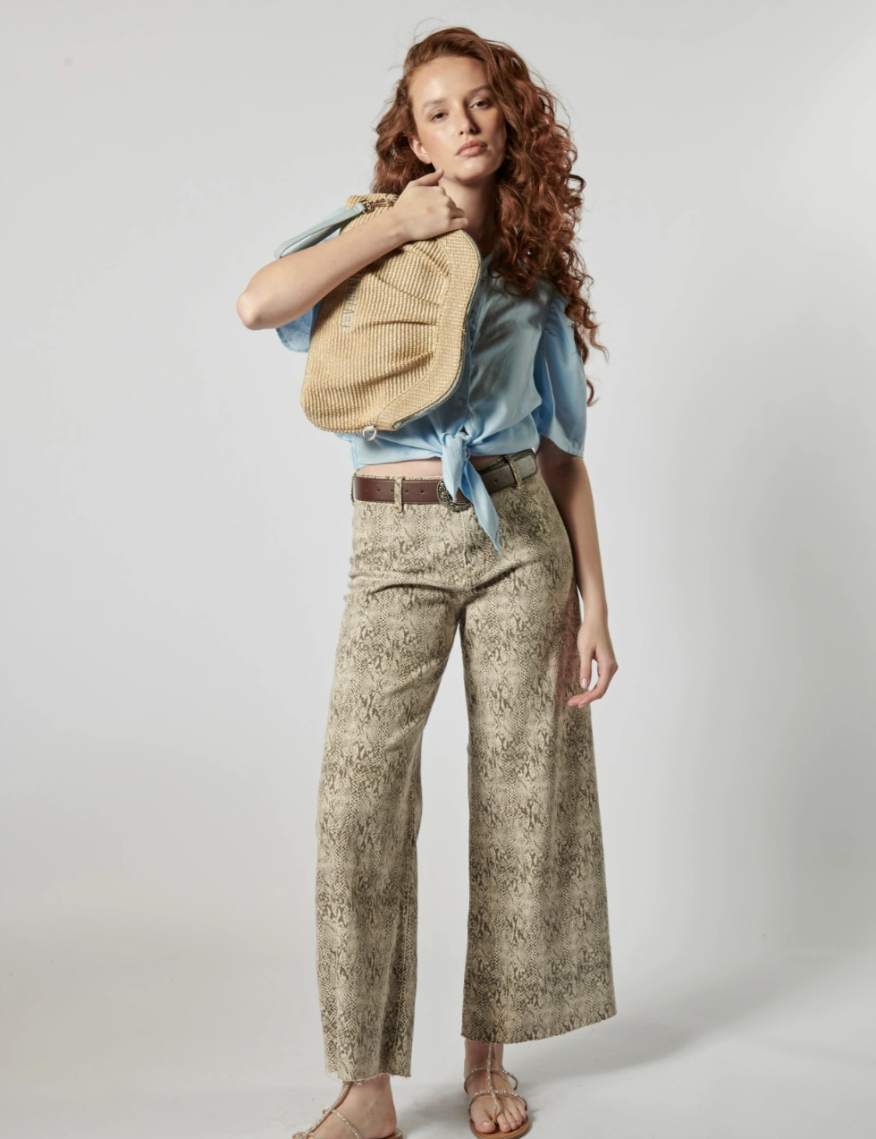 Modelo usando jeans culotte animal print con blusa celeste y bolso tejido, estilo urbano