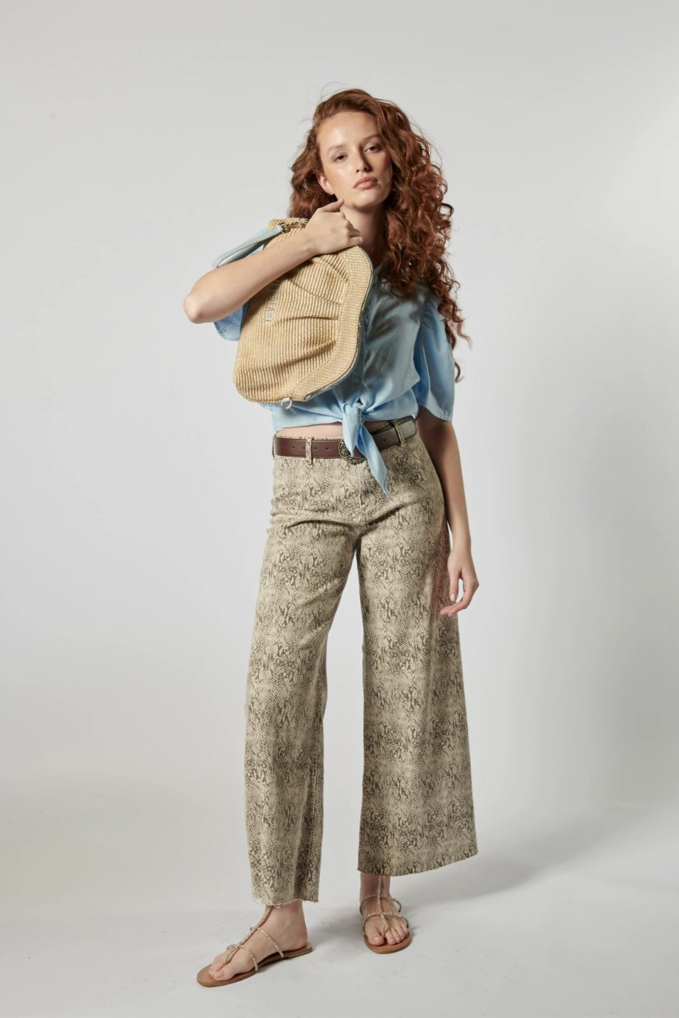 Modelo usando jeans culotte animal print con blusa celeste y bolso tejido, estilo urbano