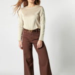 Modelo usando jeans culotte liso color café profundo con blusa beige y cinturón ancho
