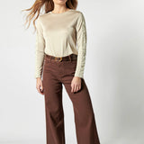 Modelo usando jeans culotte liso color café profundo con blusa beige y cinturón ancho
