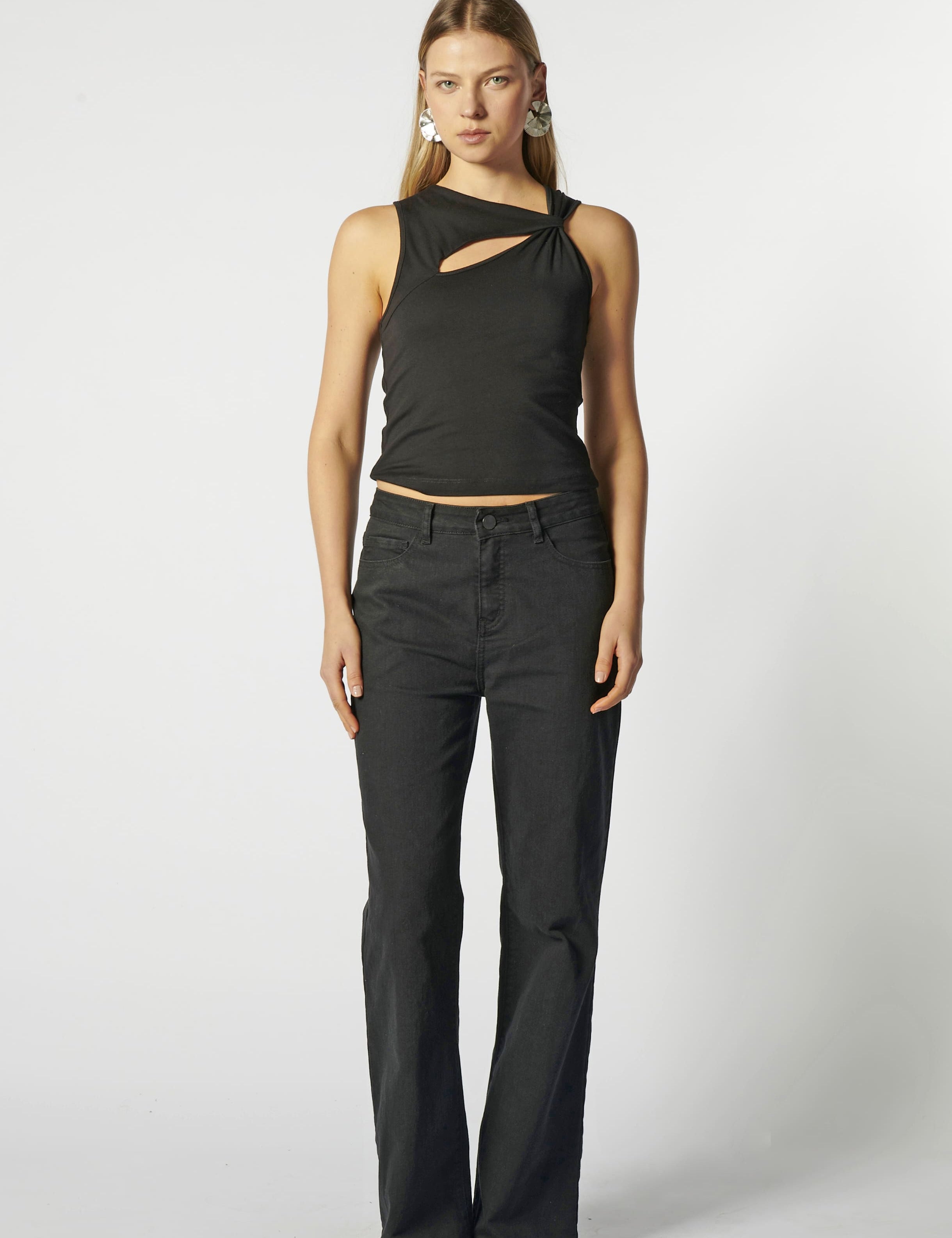 Modelo con jeans flare negro y top negro estructurado, vista frontal