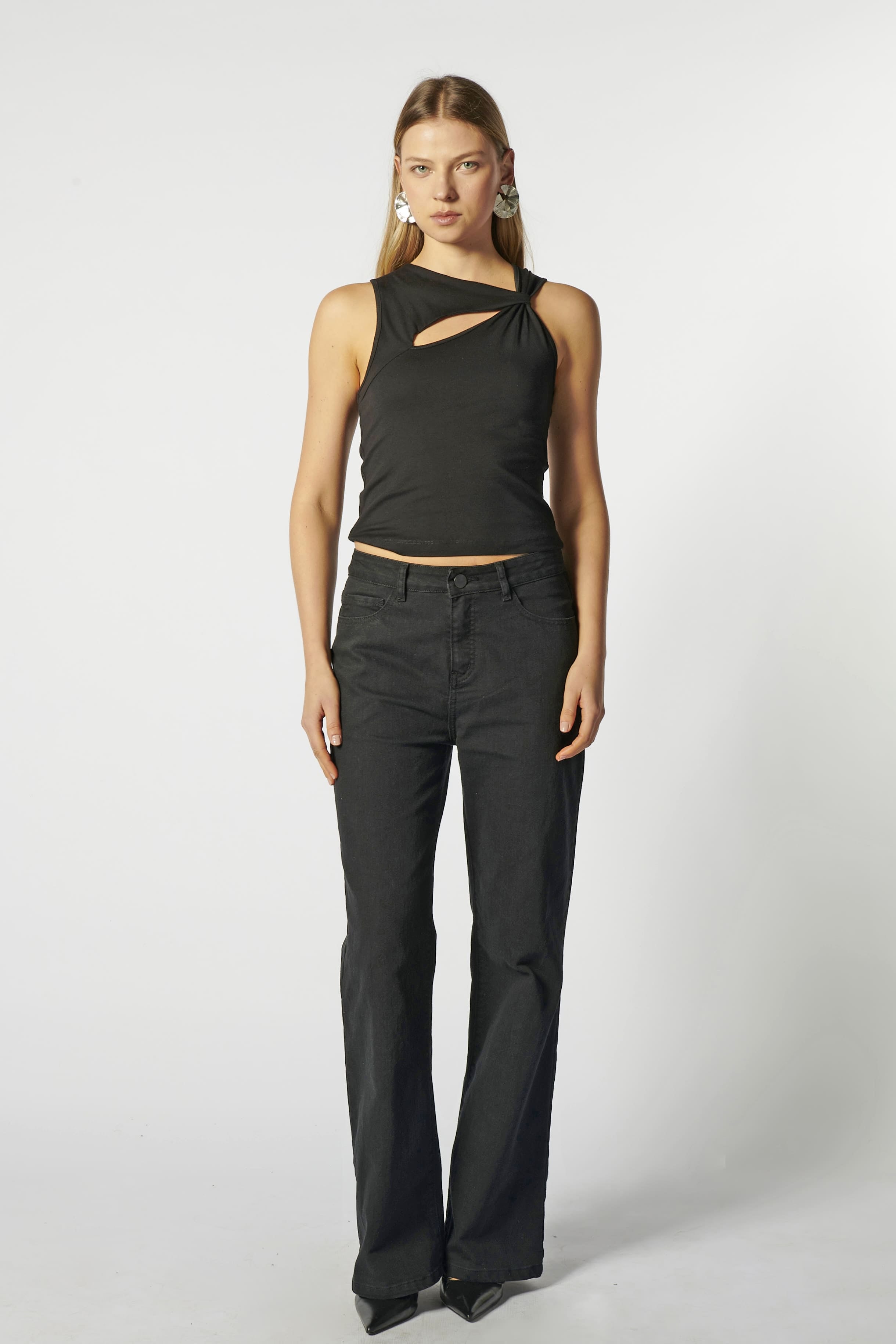Modelo con jeans flare negro y top negro estructurado, vista frontal