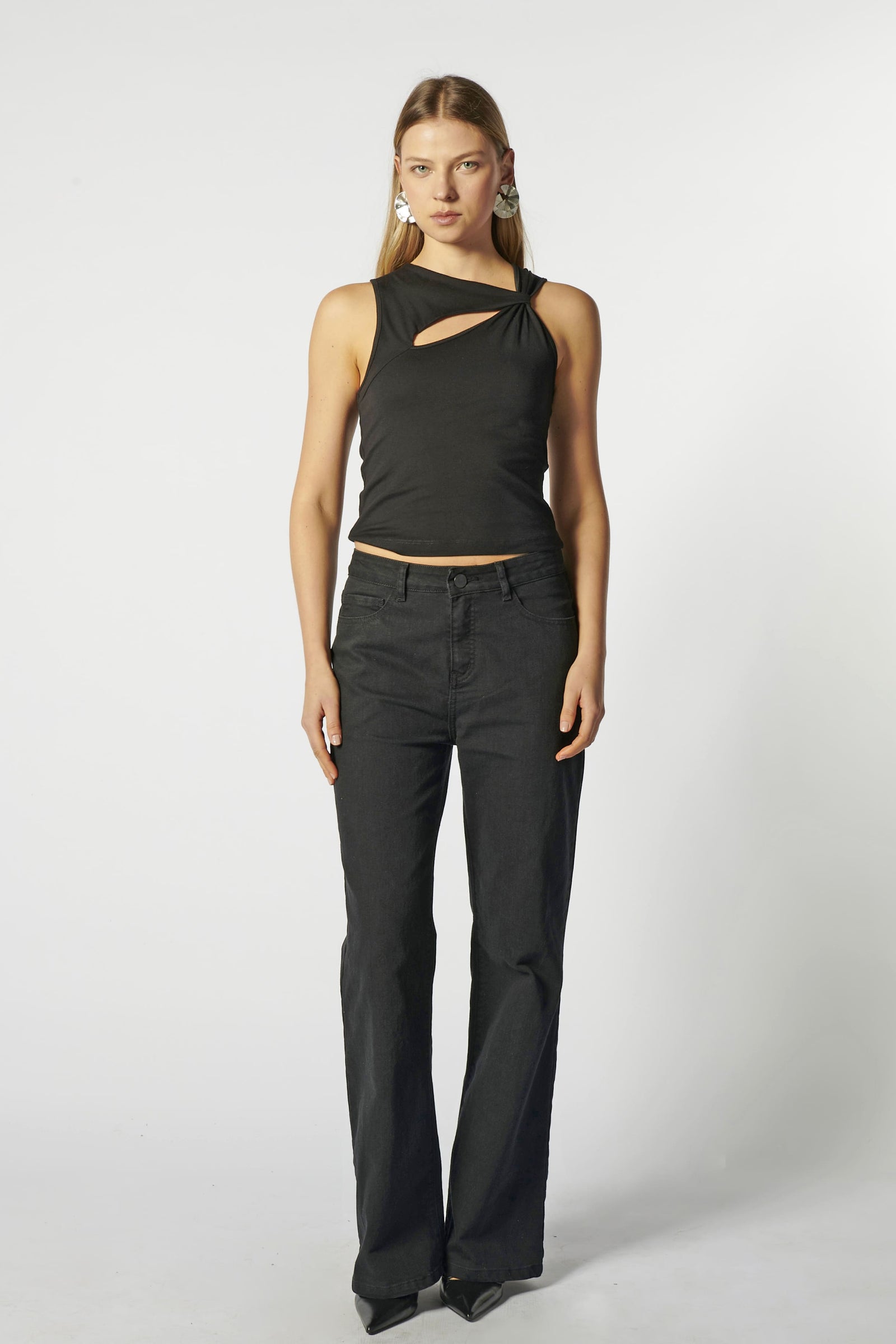 Modelo con jeans flare negro y top negro estructurado, vista frontal