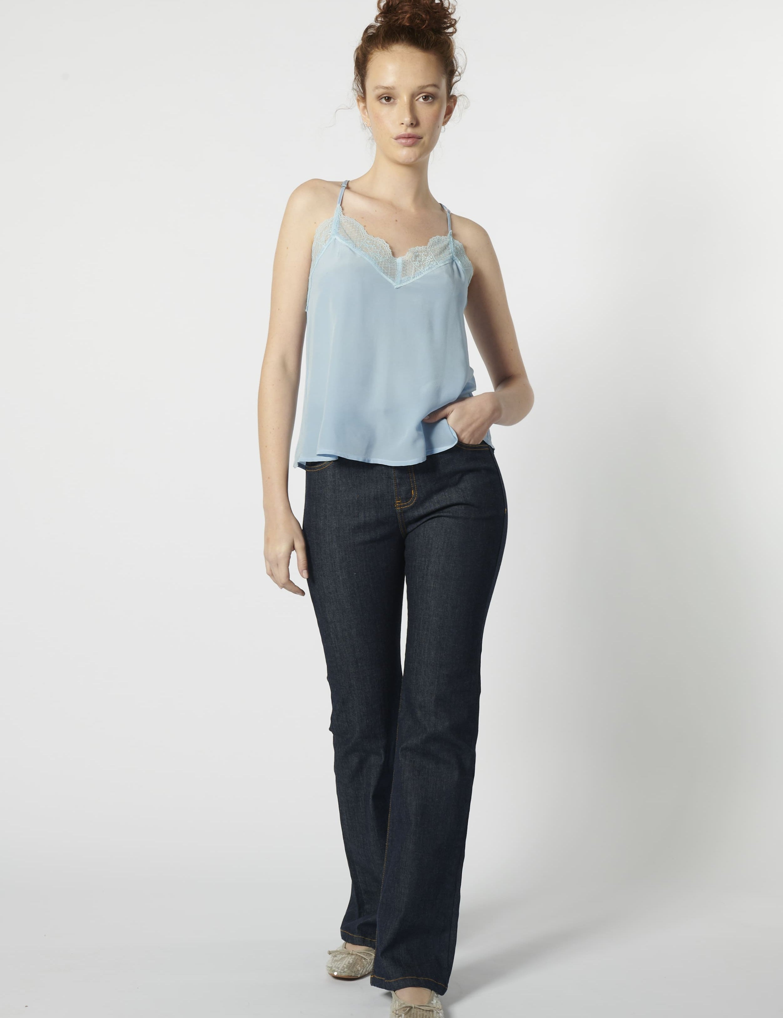 Modelo usando jeans flare mujer azul oscuro con top celeste, calce ajustado y pierna acampanada