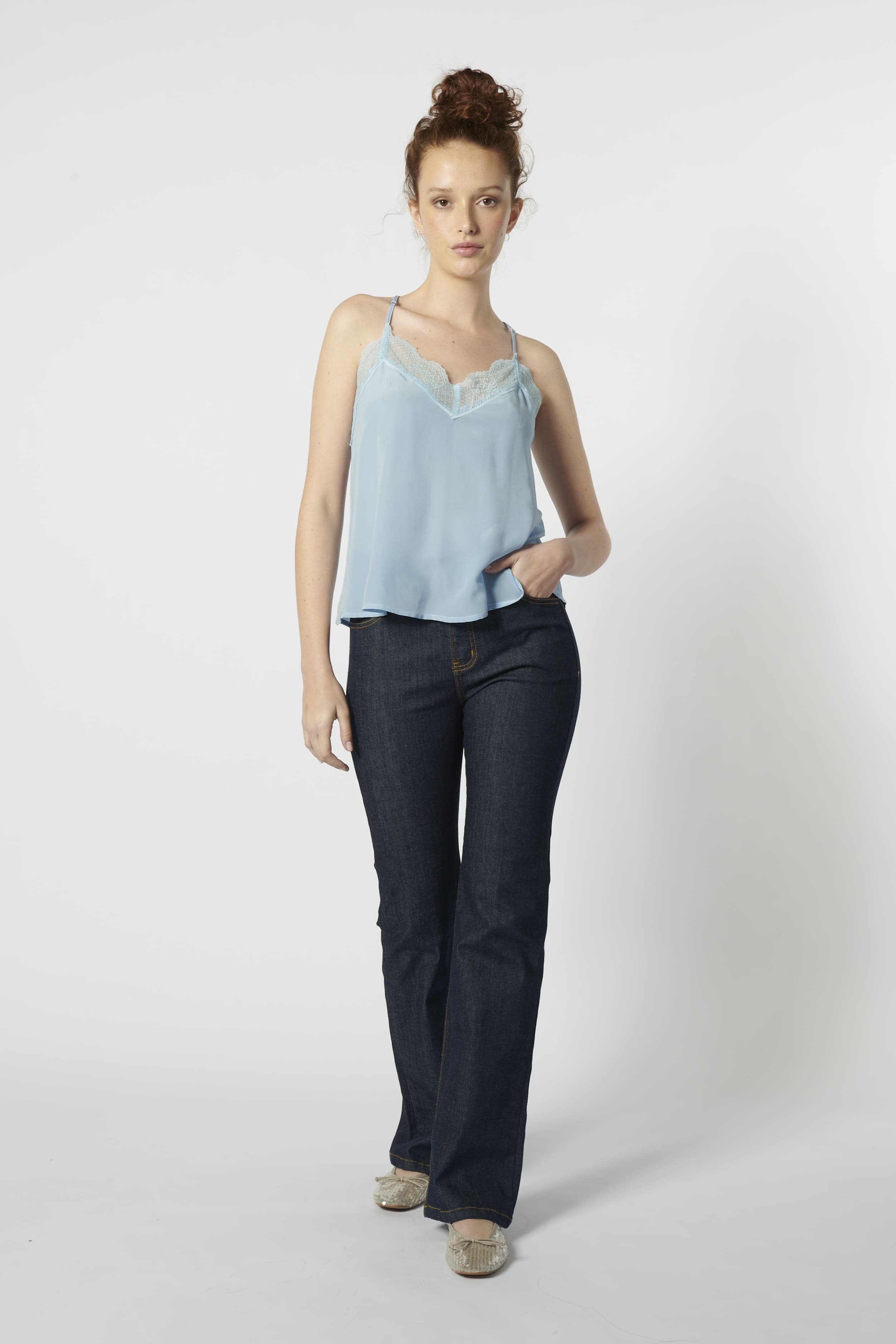 Modelo usando jeans flare mujer azul oscuro con top celeste, calce ajustado y pierna acampanada