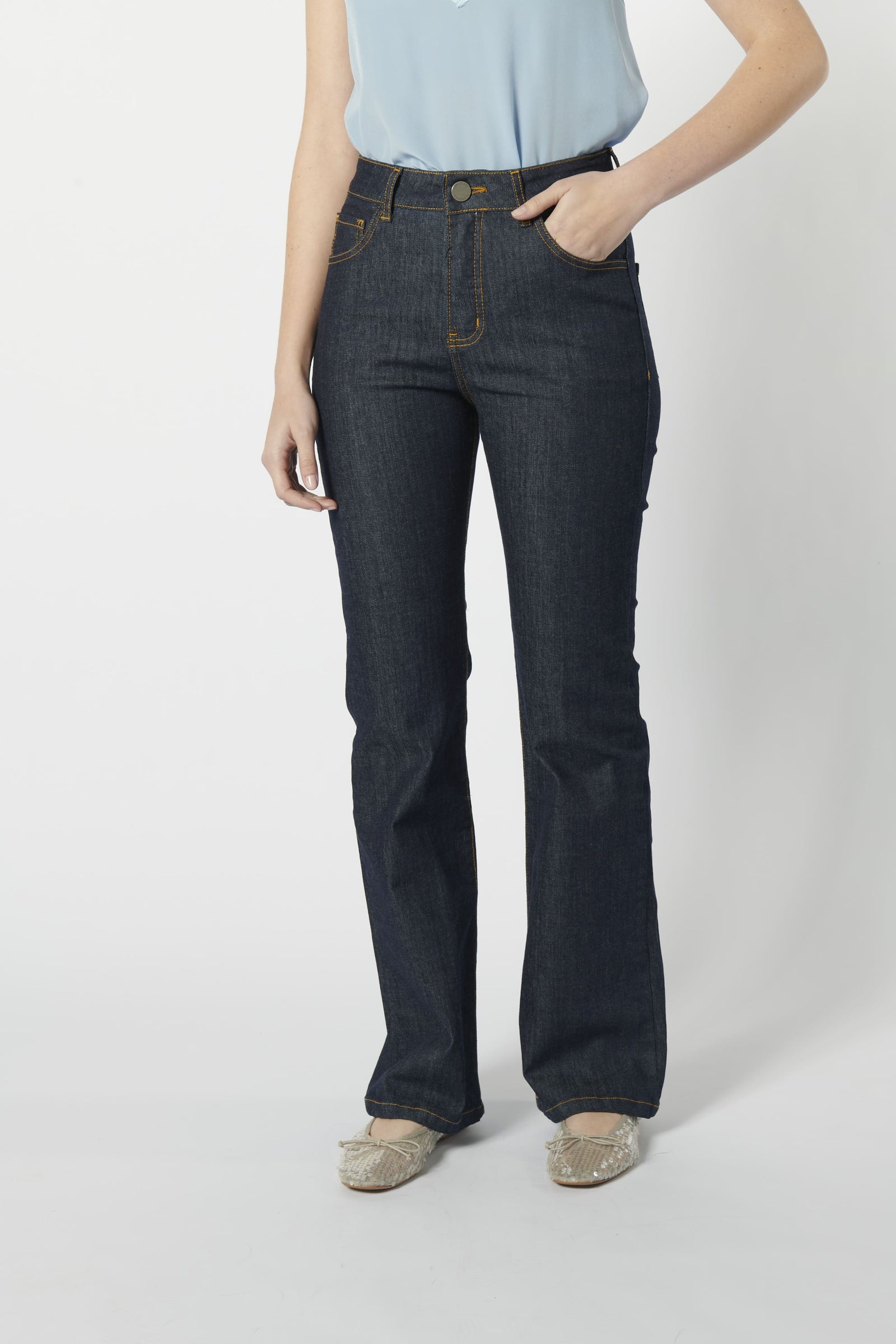 Modelo usando jeans flare mujer azul oscuro con top celeste, calce ajustado y pierna acampanada