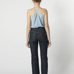 Vista trasera de jeans flare azul oscuro con top de tirantes cruzado de color celeste