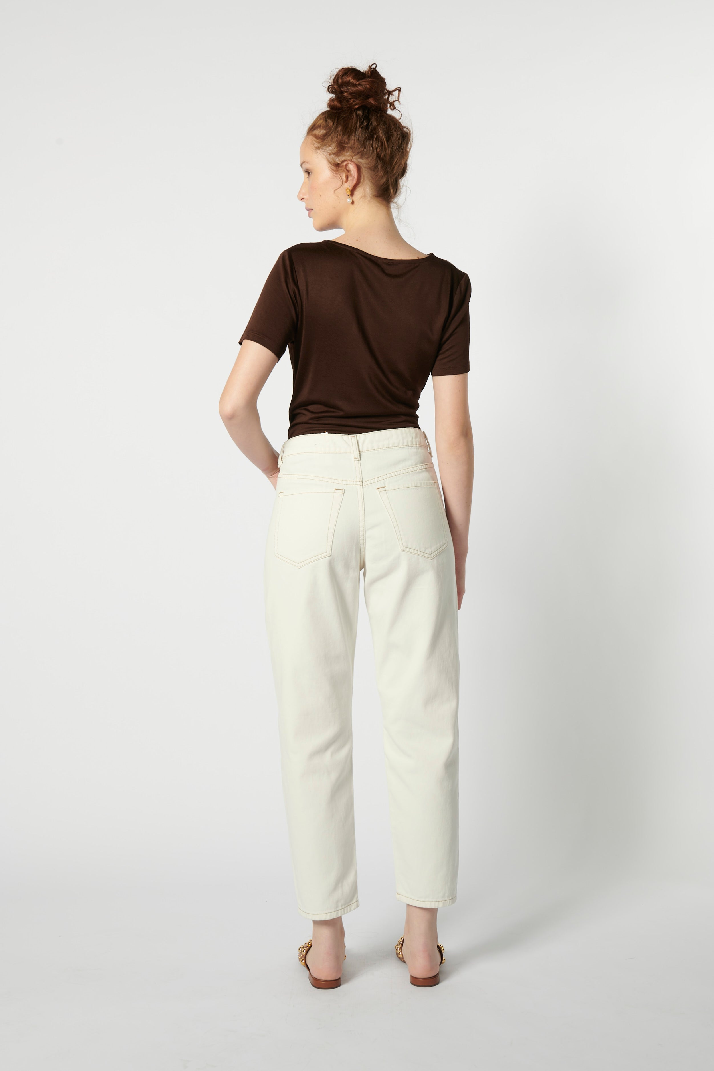 Modelo usando jeans mom fit blancos de espalda