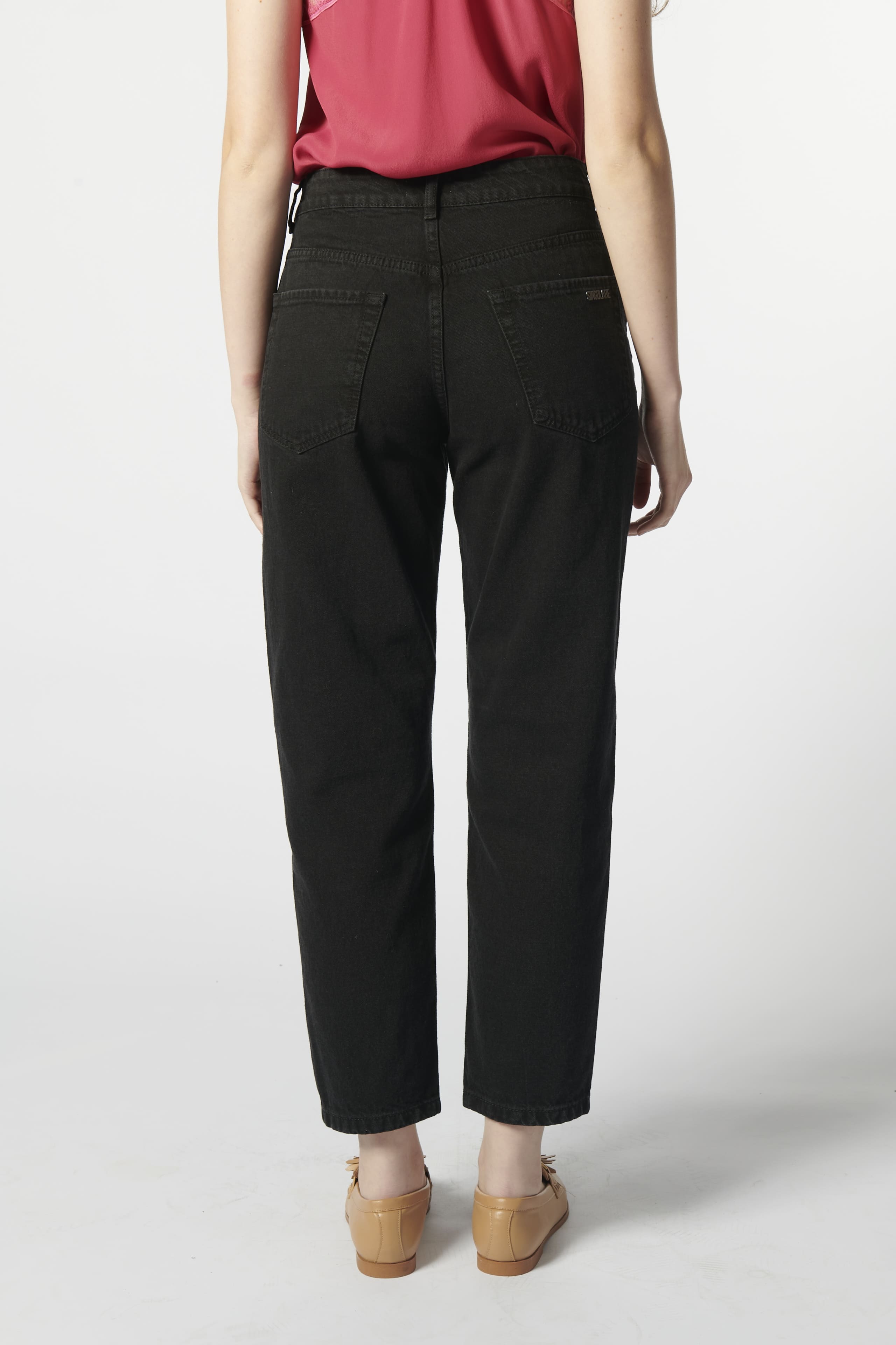 Modelo usando jeans mom fit negros detalle reverso