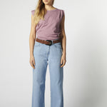 Modelo con jeans relajado color celeste claro y polera sin mangas morada
