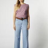 Modelo con jeans relajado color celeste claro y polera sin mangas morada
