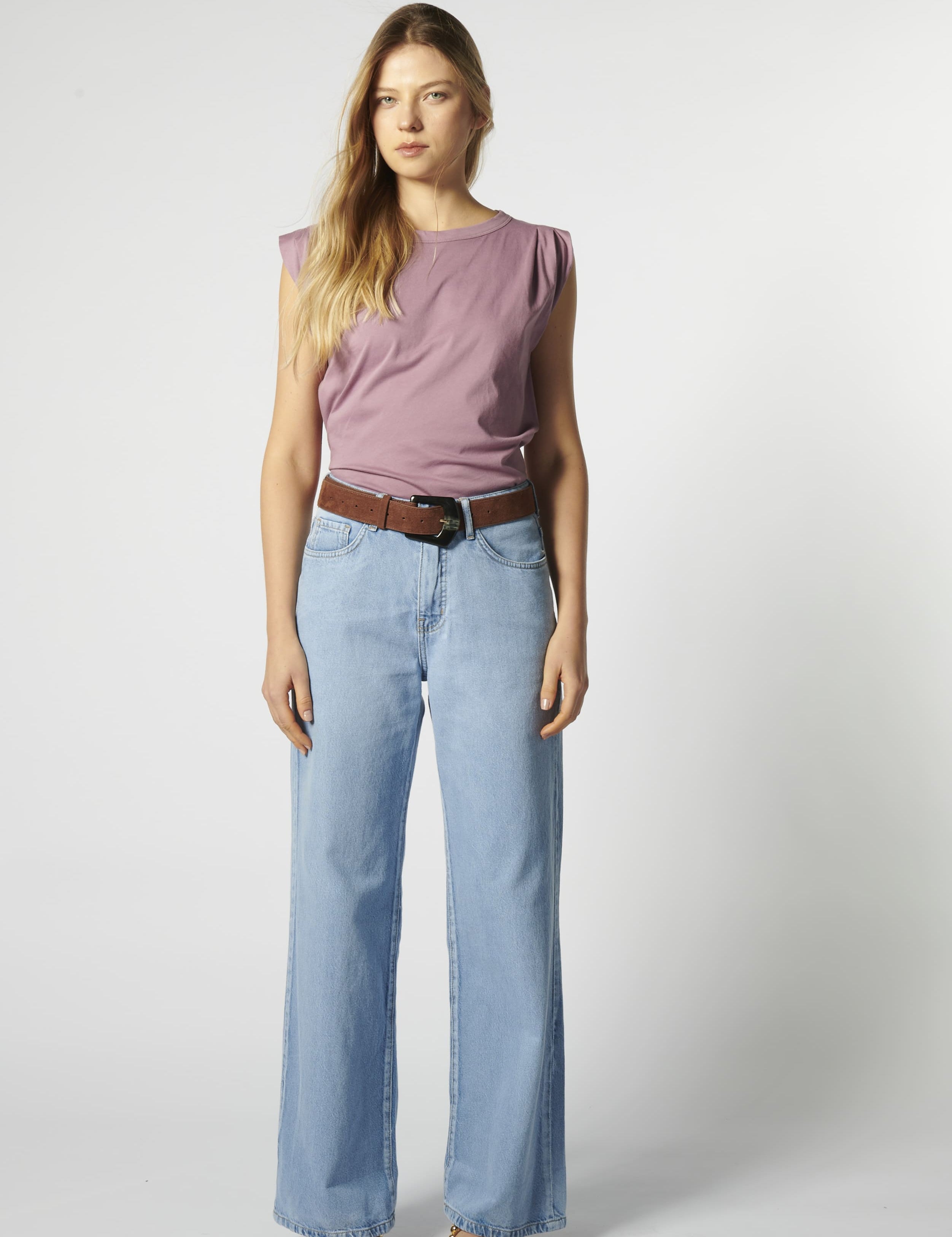 Modelo con jeans relajado color celeste claro y polera sin mangas morada
