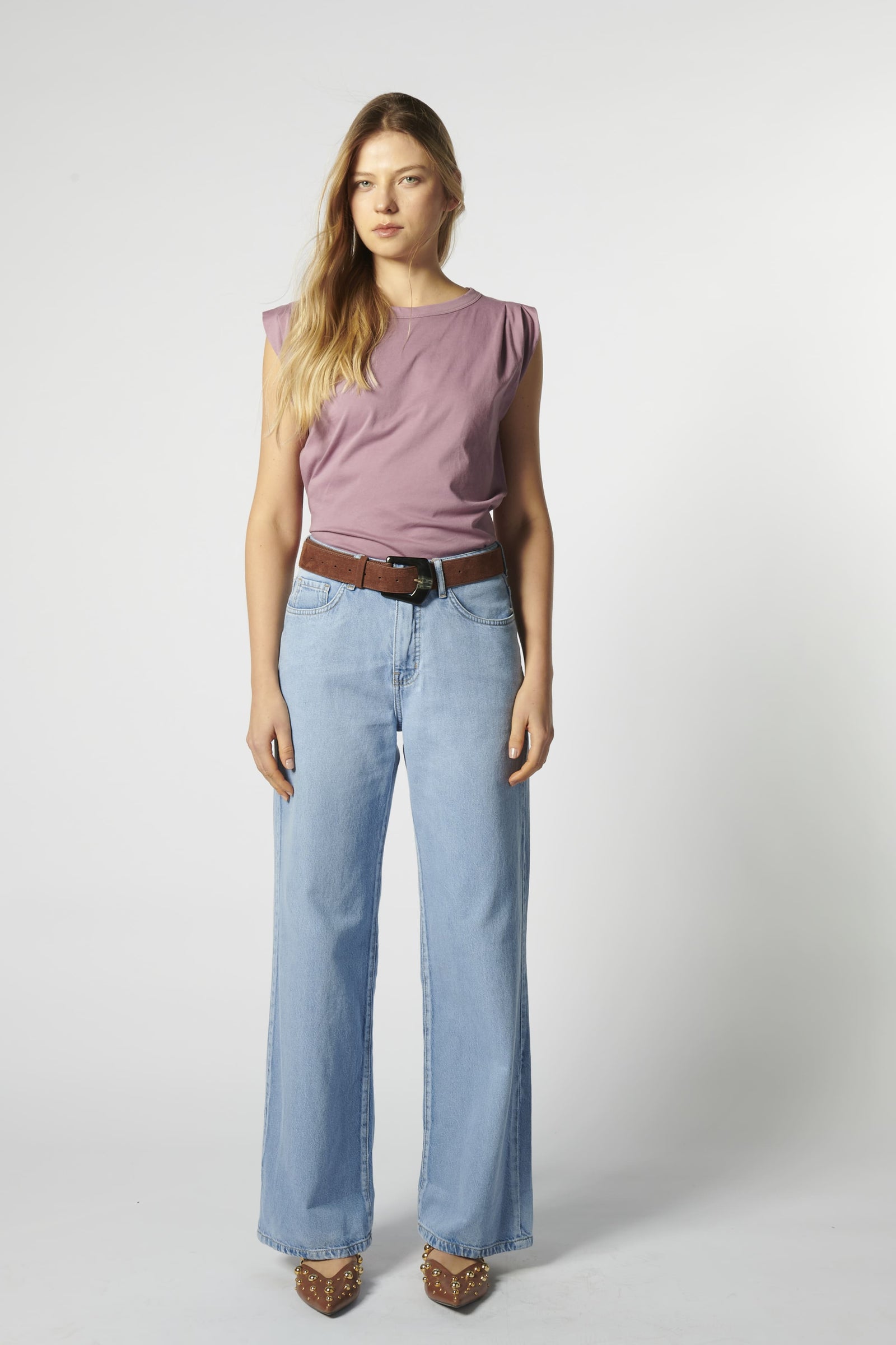 Modelo con jeans relajado color celeste claro y polera sin mangas morada
