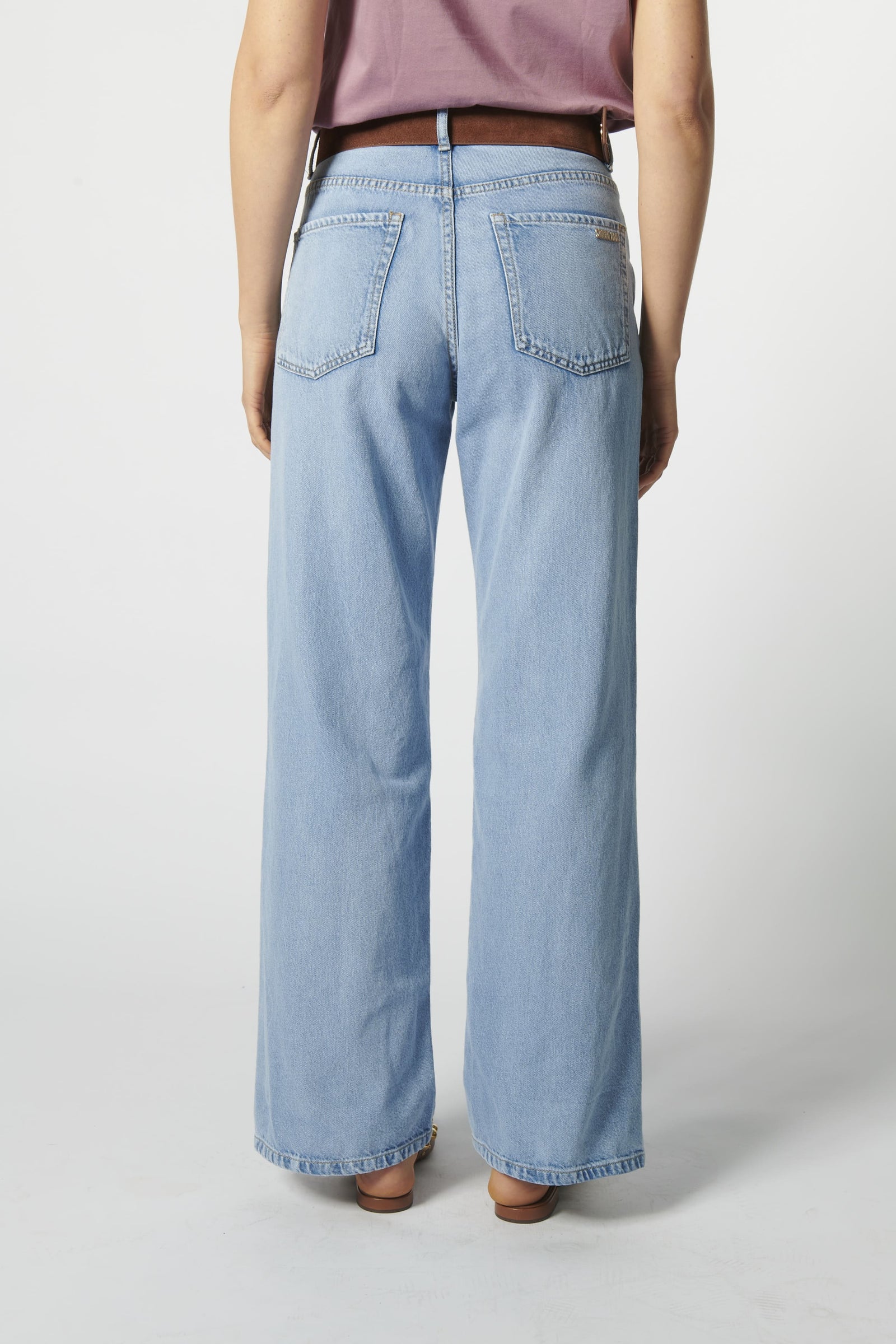 Modelo con jeans relajado color celeste claro y polera sin mangas morada
