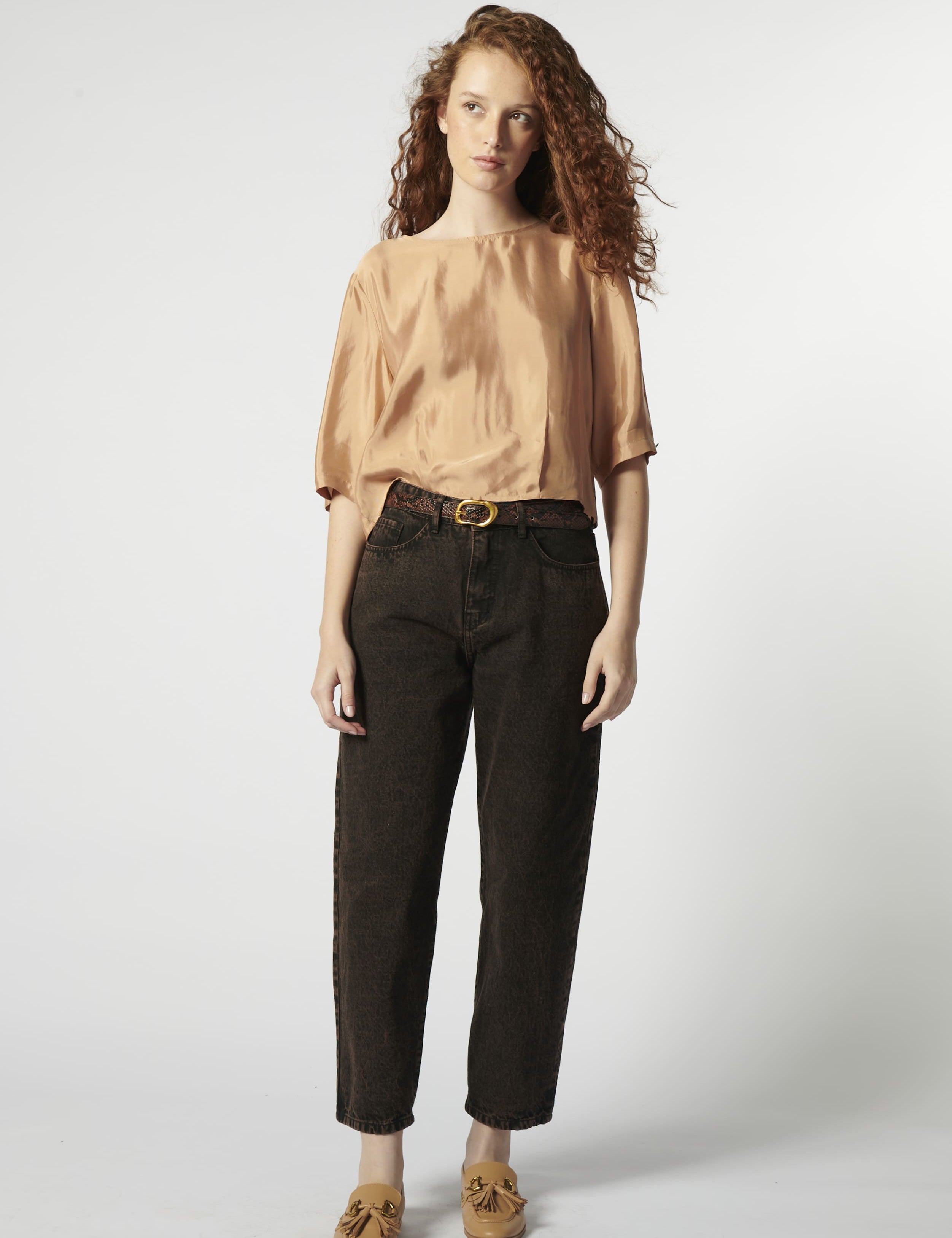 Modelo con jeans barrel color ladrillo oscuro y blusa fluida rosa palo

