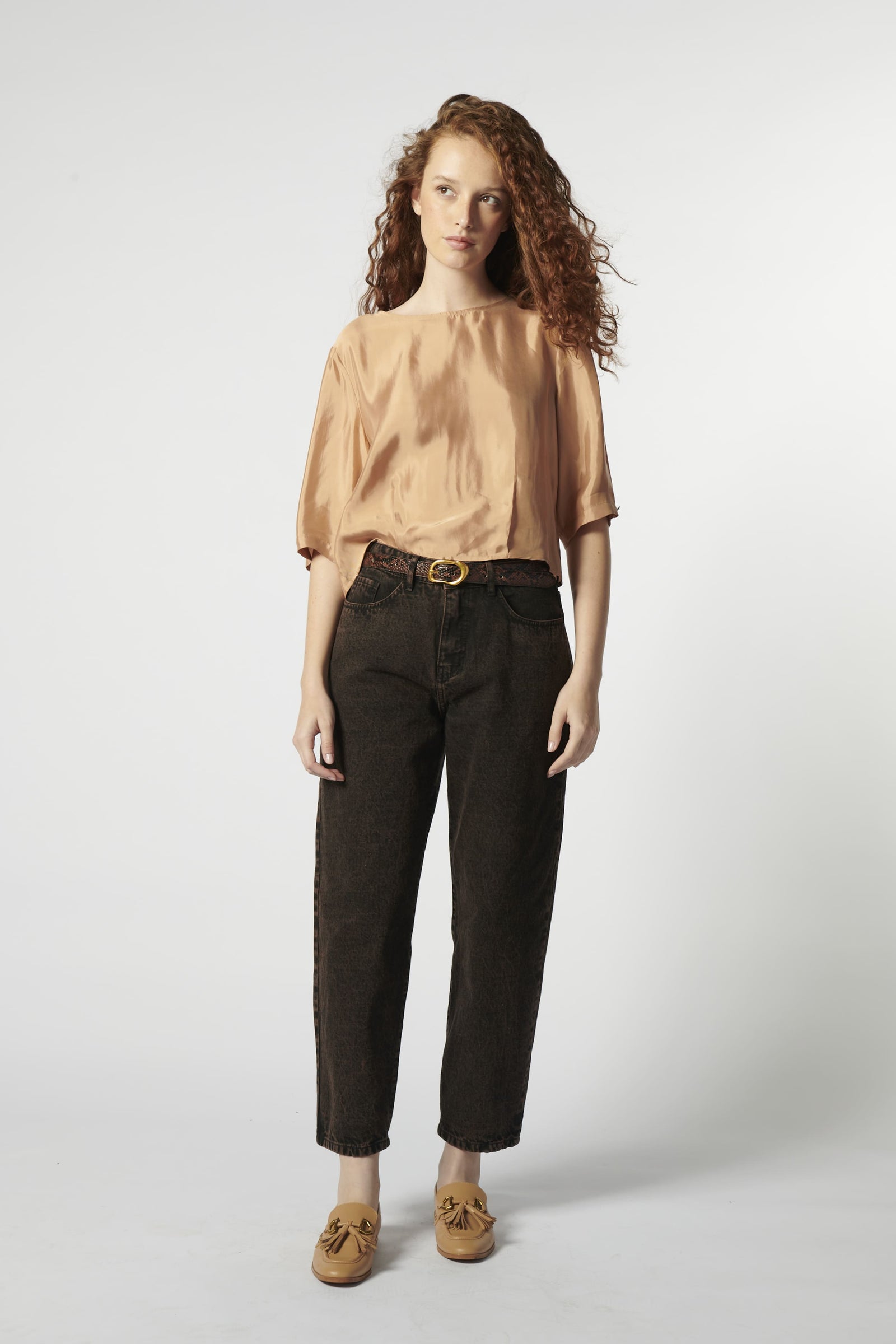 Modelo con jeans barrel color ladrillo oscuro y blusa fluida rosa palo
