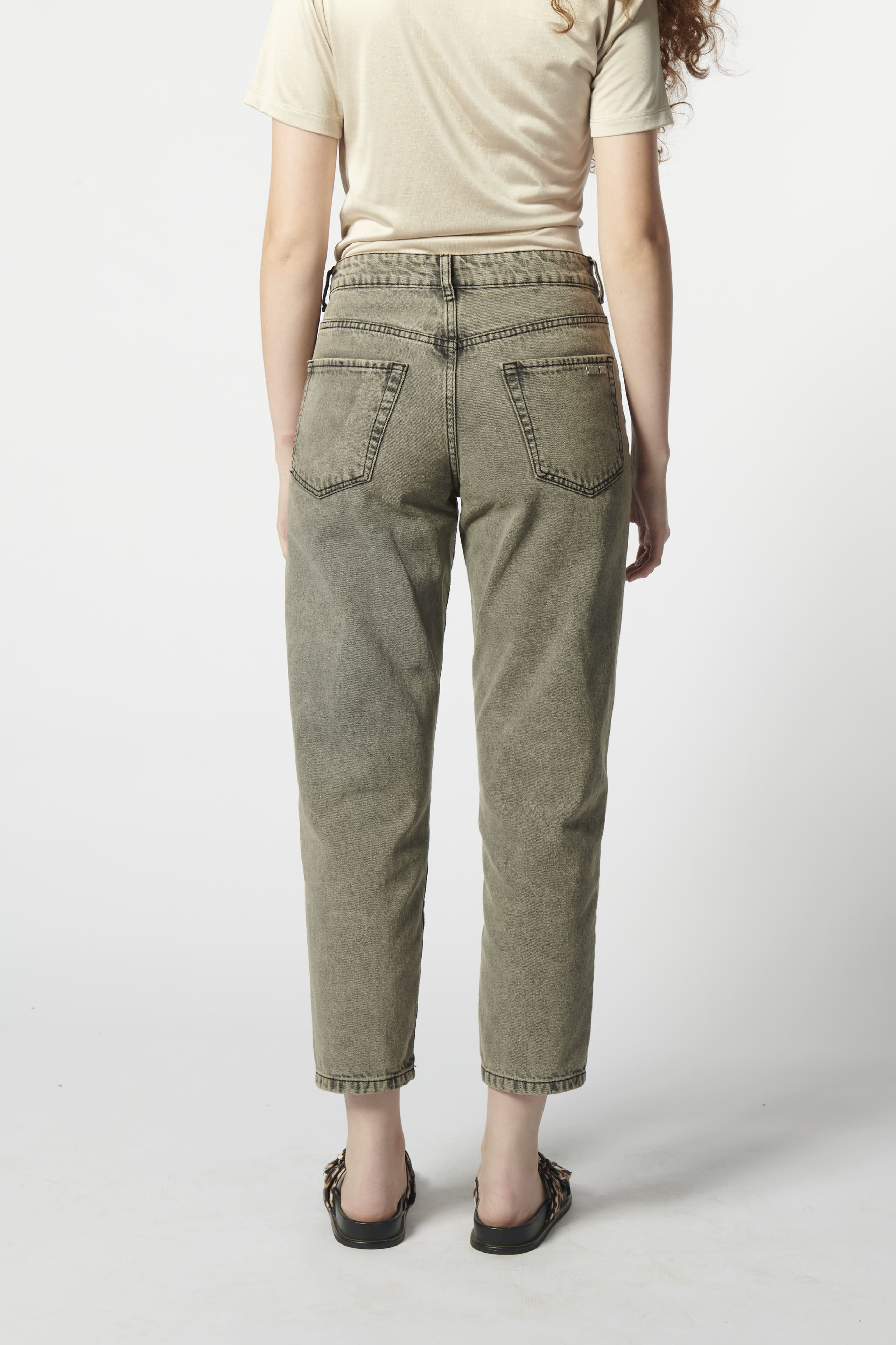 Modelo usando jeans mom fit negros detalle zoom posterior
