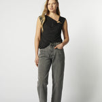 Modelo con jeans barrel gris y blusa sin mangas negra, vista frontal
