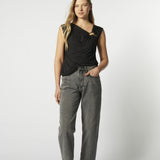 Modelo con jeans barrel gris y blusa sin mangas negra, vista frontal
