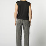 Vista trasera jeans barrel gris con blusa sin mangas negra
