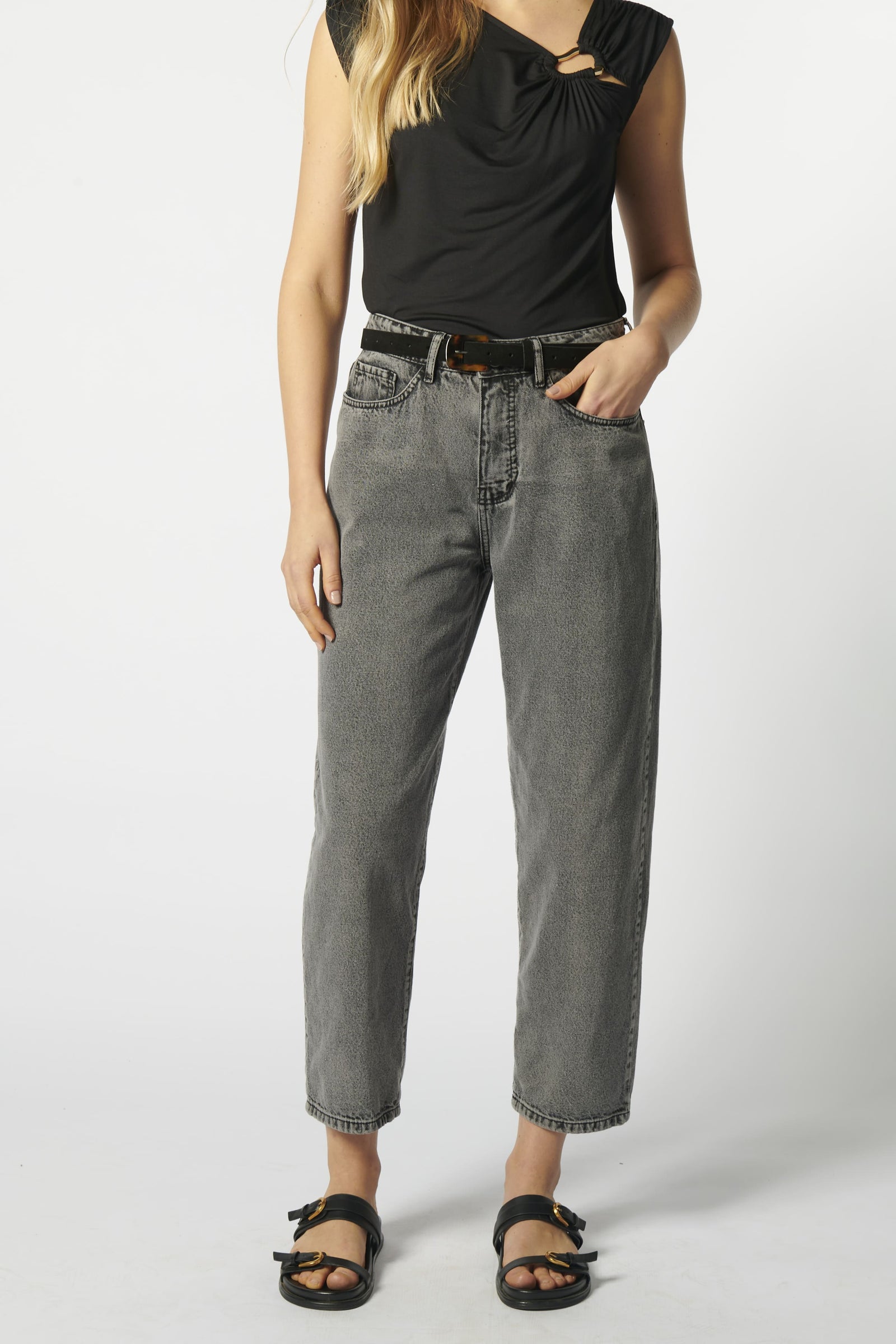 Modelo con jeans barrel gris y blusa sin mangas negra, vista frontal
