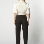 Modelo usando jeans mom fit chocolate con camisa blanca de espalda