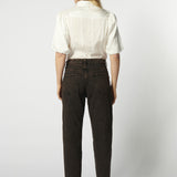 Modelo usando jeans mom fit chocolate con camisa blanca de espalda
