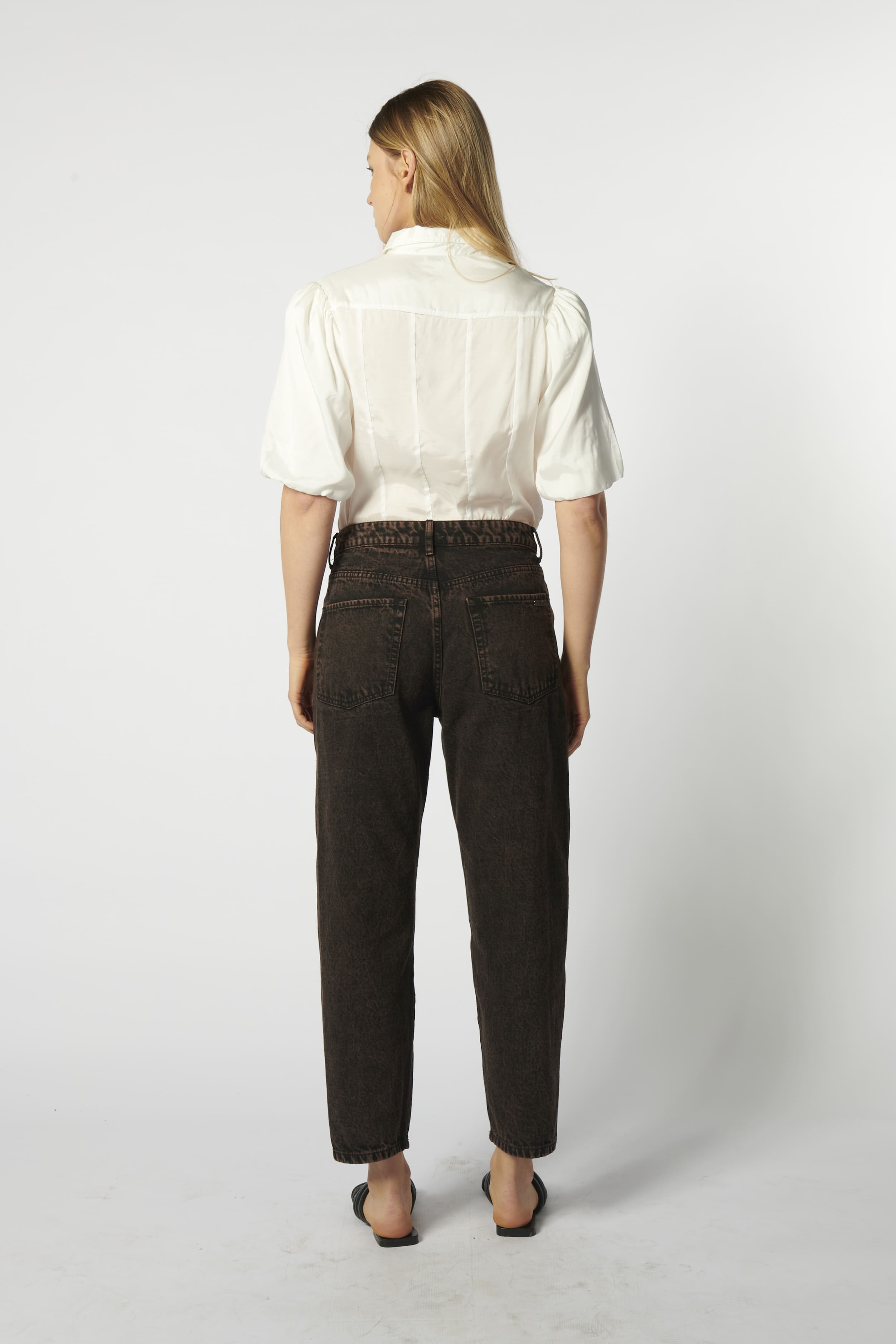 Modelo usando jeans mom fit chocolate con camisa blanca de espalda