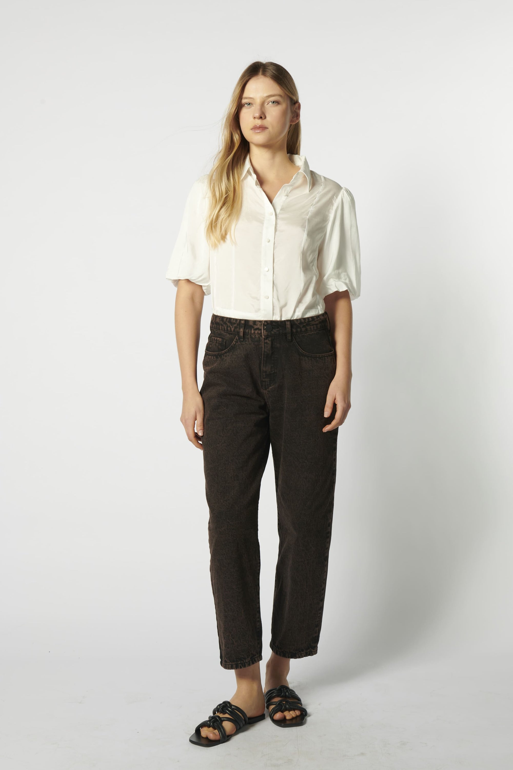 Modelo usando jeans mom fit chocolate con camisa blanca