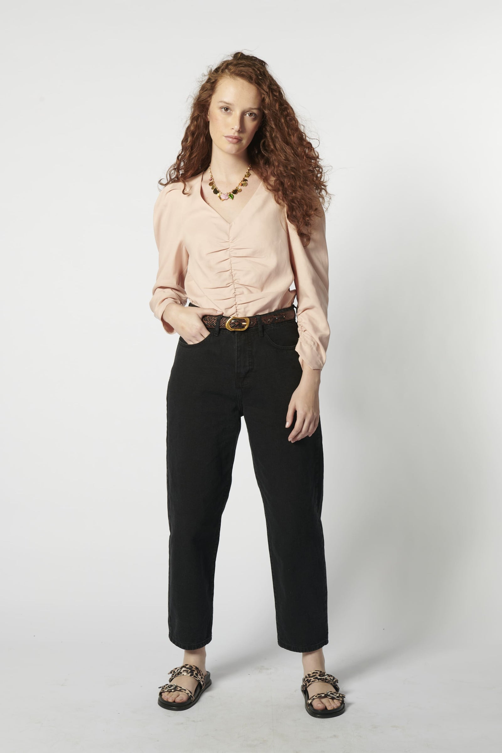 Modelo usando jeans barrel mujer color negro con blusa rosa y cinturón