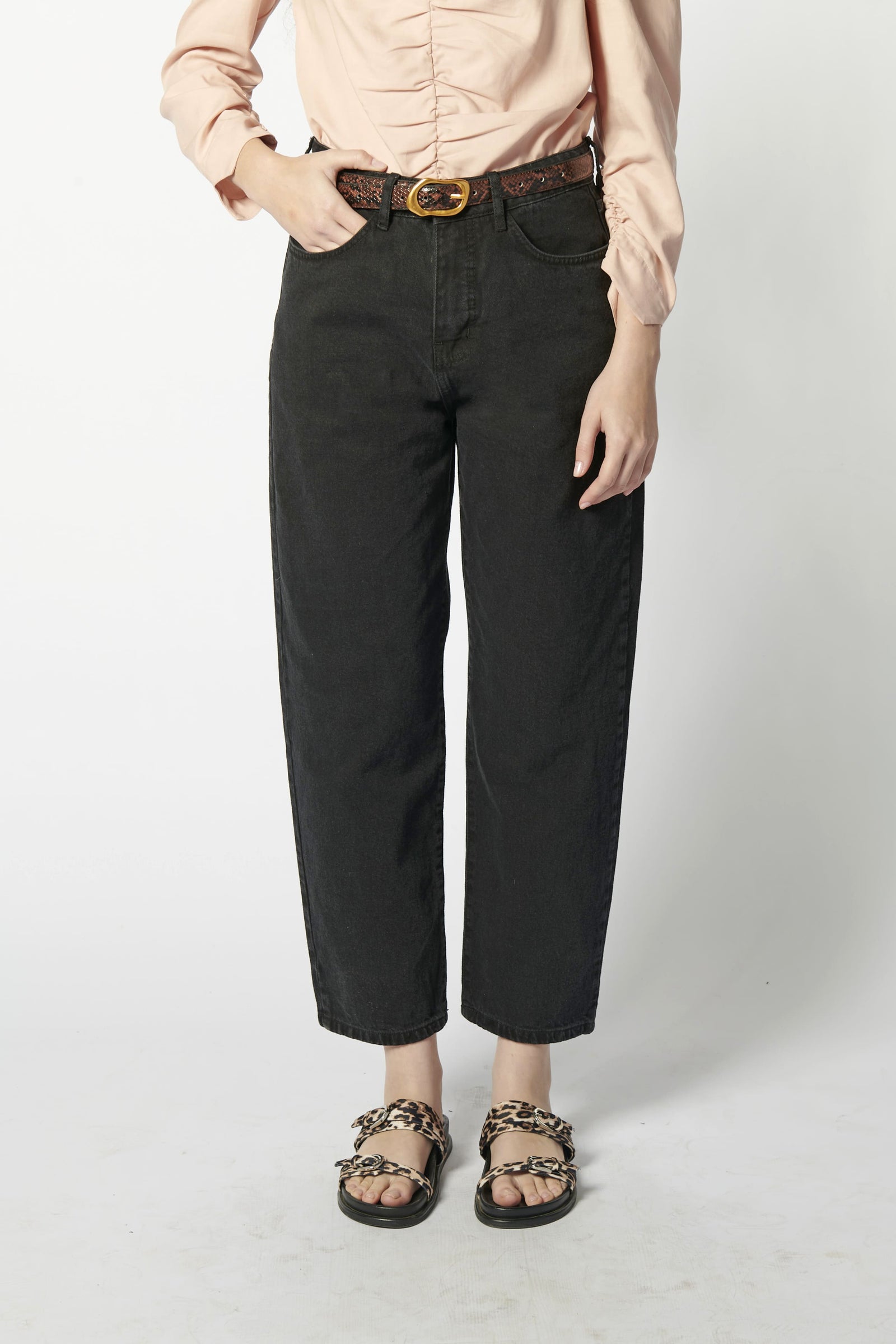 Modelo usando jeans barrel mujer color negro con blusa rosa y cinturón