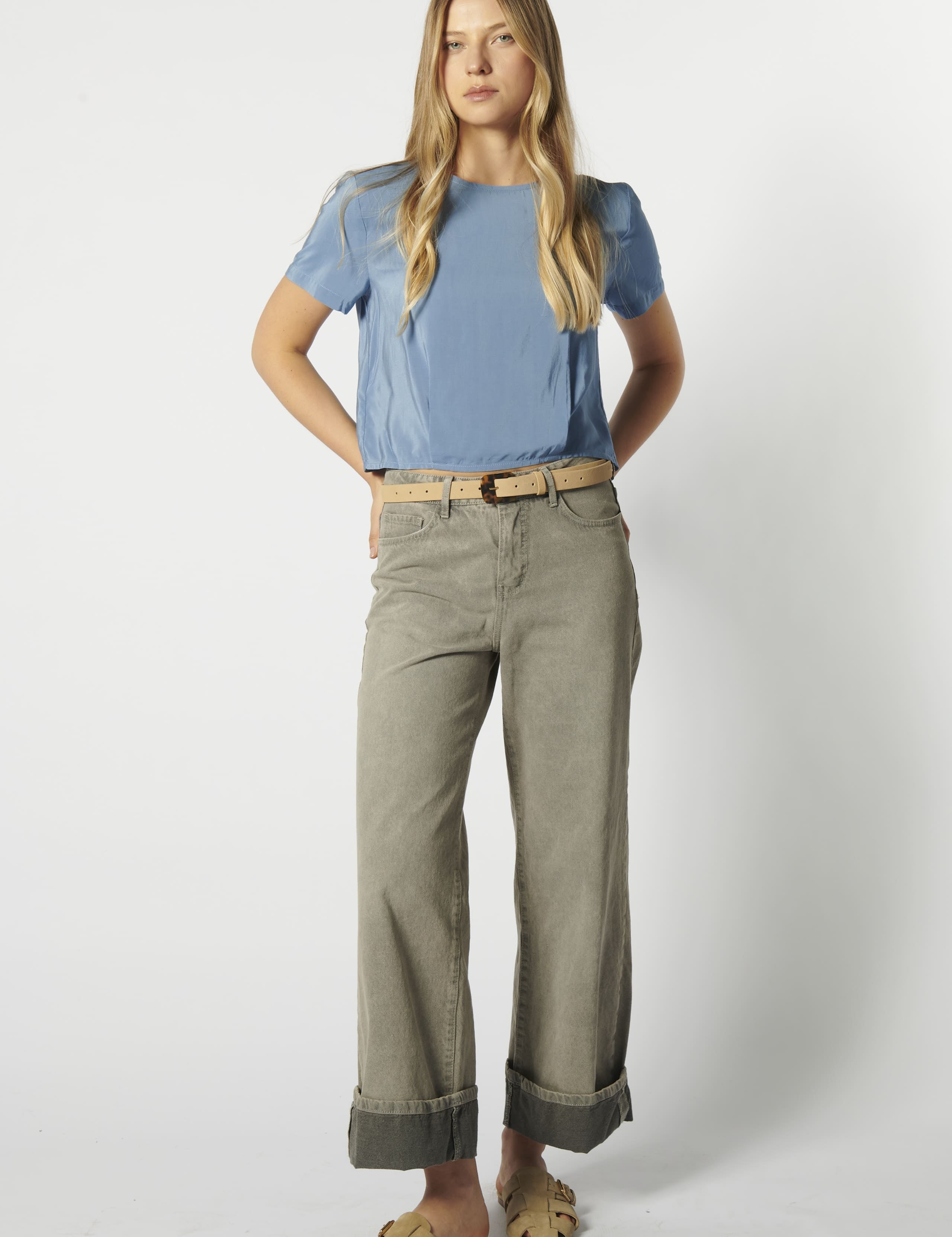 Modelo usando jeans relajado color arena con polera celeste