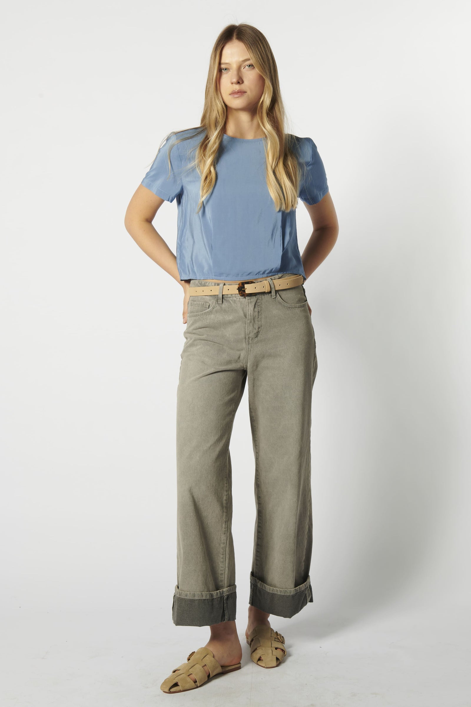 Modelo usando jeans relajado color arena con polera celeste