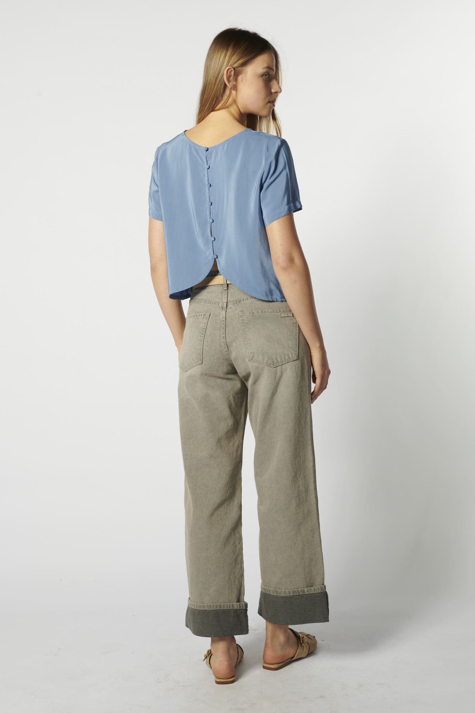 Modelo usando jeans relajado color arena con polera celeste