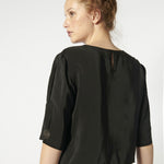 Blusa Tou Nemi de color blanco y diseño simple, mostrada en la imagen con detalles suaves y estilo elegante.