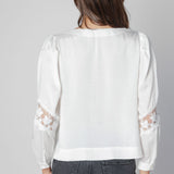 Blusa Marie de la marca O-2025-606 en color blanco, con diseño elegante y mangas largas, para un estilo sofisticado.